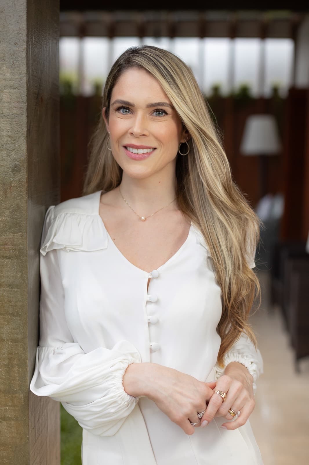 Dra. Luíse Pezzin em pé, vestindo blusa branca, em ambiente com iluminação natural