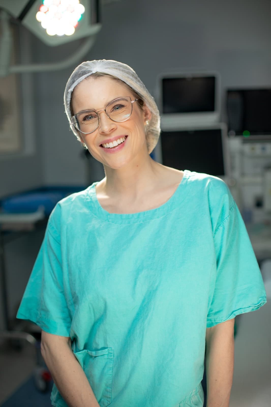 Dra. Luíse Pezzin sorrindo, em traje cirúrgico, em ambiente hospitalar
