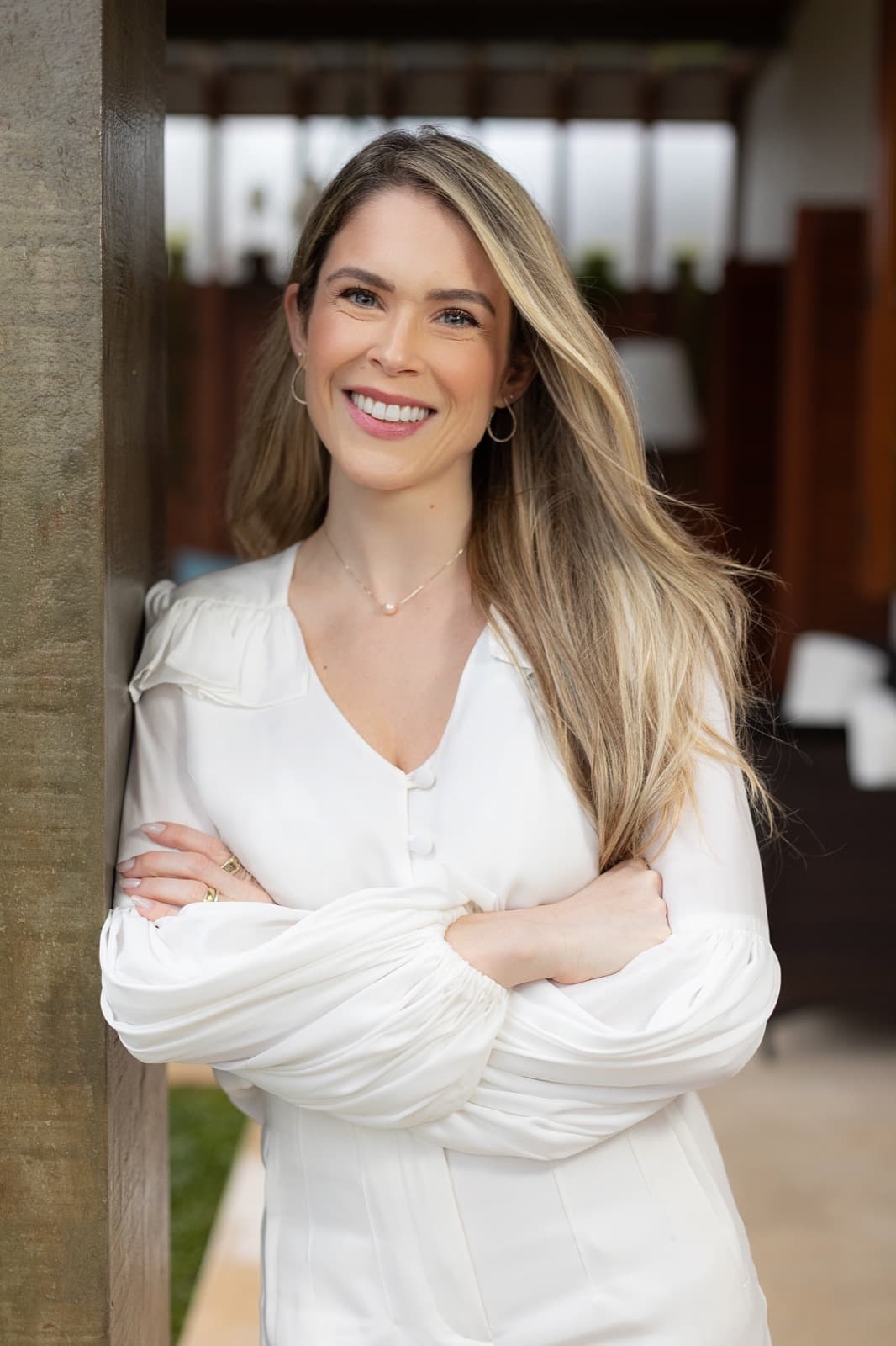 Retrato da Dra. Luíse Pezzin, médica otorrinolaringologista, de braços cruzados, vestindo blusa branca